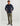 Man wearing navy fleece pullover with quarter-snap collar and orange-trimmed pockets, paired with khaki pants.