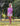 Woman wearing a pink long-sleeve top and white shorts standing outdoors.