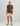 Brown short-sleeve t-shirt with small chest logo worn with cream shorts and cap.