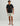 Black short-sleeve t-shirt with chest pocket and Huk logo, paired with cream and gray patterned shorts.