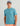 Teal short-sleeve t-shirt with chest pocket and Huk logo, worn with blue cap and coral shorts.