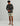 Charcoal long-sleeve shirt with chest pocket and circular logo, worn with cream patterned shorts.