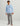 Light blue long sleeve tee with chest pocket and circular logo print, paired with gray pants.