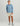 Man wearing blue long-sleeve crew neck shirt with HUK logo and text, paired with cream shorts and gray water shoes.