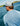 Man wearing light blue crew neck shirt with white shoulders on a boat, viewed from behind.