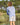 Person wearing light blue long-sleeve crew neck shirt and tan shorts while holding a fishing rod by water.