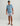 Man wearing light blue short-sleeve crew neck shirt with "Huk" logo and gray patterned shorts.