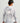 Gray and white camouflage hoodie with drawstring hood and orange text detail on back, worn with black cap.