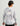 Gray and white camouflage hoodie with drawstring hood and orange text detail on back, worn with black cap.