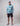 Man wearing turquoise and white textured Huk hoodie with black shorts and gray cap.