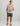 Light gray short-sleeve crew neck tee with small fish graphic on chest, worn with navy camo shorts.