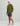 Olive green hoodie with HUK branding on chest and sleeve, worn with navy patterned shorts and white cap.