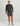 Black camo 1/4 zip pullover with Huk logo worn with olive shorts and gray socks.