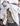 White fleece shacket with button front and chest pocket, worn open over patterned shirt.