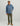 Man wearing slate blue Huk hoodie with logo, olive pants, and tan boots.