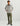 Man wearing light gray fleece pullover with snap placket and orange pocket trim, paired with olive pants and black sneakers.
