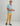 Man wearing light blue button-down shirt with short sleeves and yellow chinos with black slip-on shoes.