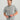 Gray short-sleeve button-down shirt with white abstract pattern worn by man against neutral background.