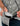 Gray button-down shirt with white botanical print worn by person holding black sunglasses.