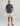 Man wearing navy blue floral short-sleeve button-down shirt with cream shorts and brown sandals.