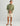 Man wearing sage green printed button-down shirt with cream shorts and brown sandals.