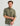 Olive-green button-down shirt with roll-tab sleeves and chest pockets, worn by man against neutral background.