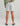 White shorts with rear pocket and drawstring waist, worn with green long-sleeve shirt.