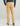 Tan pants with flat front, back pockets, and seam detail at knee, worn with dark blue long-sleeve shirt.