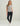 Gray v-neck tee with small palm tree graphic on chest, worn with black joggers and white sneakers.