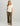 White v-neck t-shirt with small graphic text on chest, paired with olive ribbed pants.
