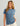 Blue short-sleeve t-shirt with chest pocket worn by woman with long brown hair.