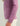 Mauve crew neck sweatshirt with "Pursuit" text down the sleeve, worn with cream pants.