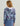 Woman wearing a cropped hoodie with purple, blue, and black abstract print and white lining at neckline.