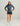 Woman wearing blue tie-dye quarter-zip hoodie with navy shorts and white sneakers.