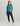 Woman wearing teal long-sleeve quarter-zip pullover with navy pants and white sneakers.