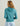 Woman wearing teal fleece hoodie with drawstring hood, shown from back view against neutral background.