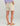 Cream shorts with flap pockets and side pockets worn with purple top and tan sandals.