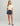 Woman wearing cream short-sleeve t-shirt with chest pocket and navy patterned swim shorts with drawstring waist.