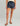 Navy volley shorts with dark blue leaf print, drawstring waist, worn with cream tank top and brown sandals.