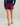 Purple shorts with elastic waistband and side pockets, worn with navy long-sleeve top and tan platform sandals.