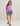Woman wearing purple half-zip pullover and multicolored abstract print shorts with drawstring waist.