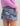Purple and teal abstract patterned shorts with side pockets, worn with a pink-purple long-sleeve top.
