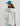 Woman wearing white hooded jacket with black collar and teal baseball cap, shown from back view.