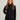 Black women's jacket with front zip closure and stand collar worn over purple undershirt.