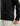 Black HUK branded jacket with full-length zipper and chest pocket worn over cream-colored pants.