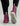 Purple and gray pull-on boots with pink striped heel tabs and white rubber soles, worn with black pants.