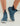 Blue wave-patterned neoprene boots with white soles, elastic sides, and striped pull tabs, worn on feet.