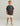 Child wearing charcoal t-shirt with yellow fish logo, cream shorts, and beige boat shoes.