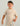 Child wearing beige t-shirt with small orange rocket graphic and patterned shorts.