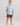 Child wearing light blue t-shirt with white logo and camouflage shorts with tan boat shoes.